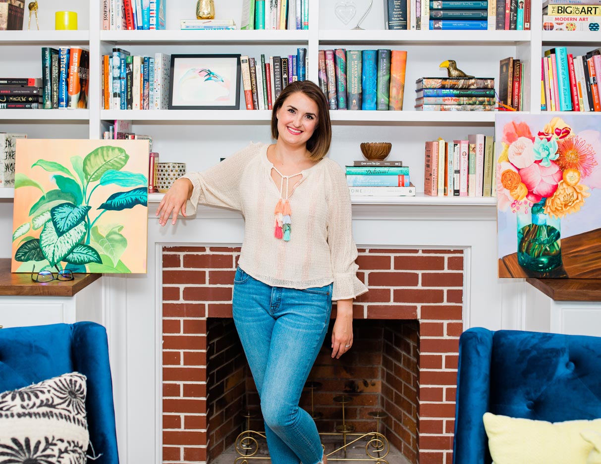 Kristina Bloom, standing in front of a fireplace mantle filled with books and artwork