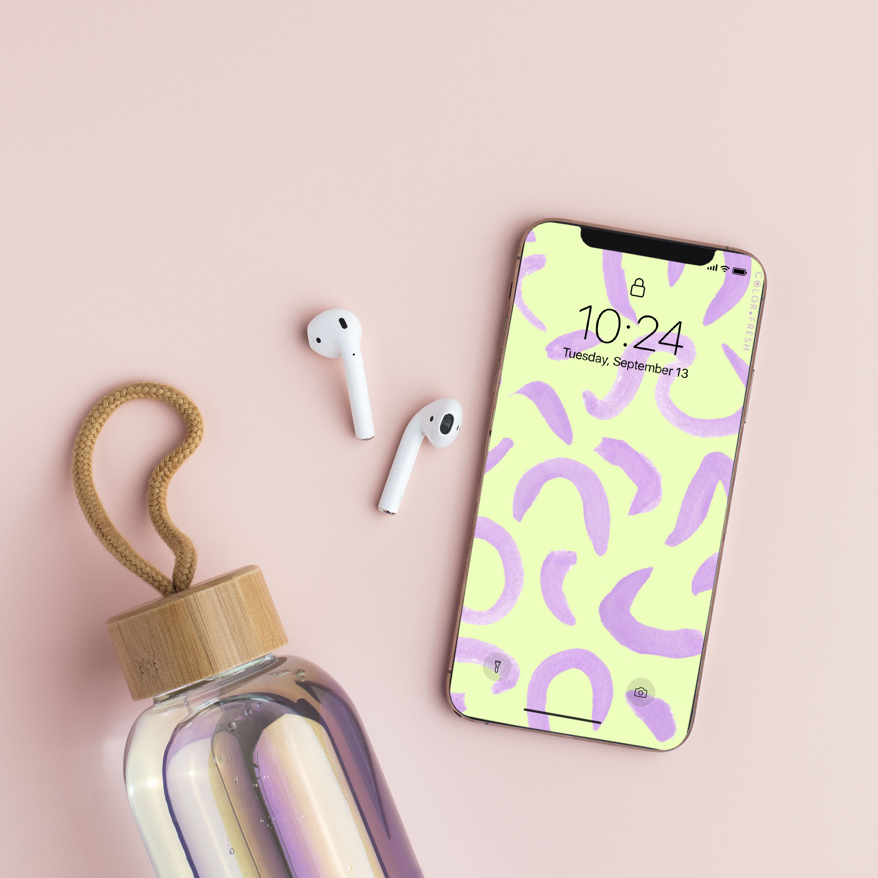 Flat lay with holographic water bottle, airpods, and iphone with painted pattern screen